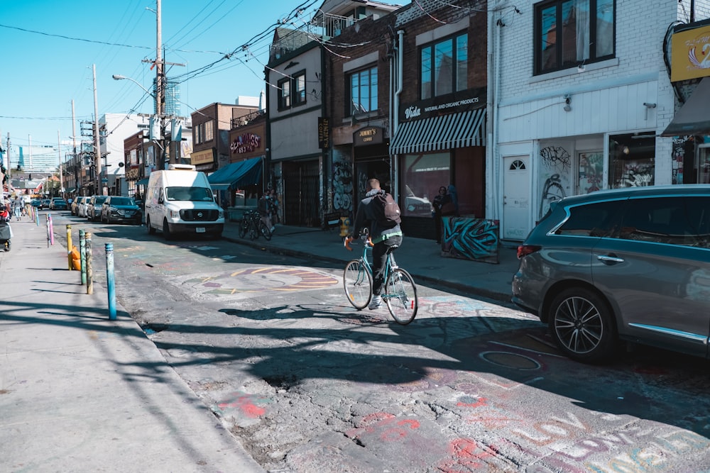 a man riding a bike down a street next to parked cars