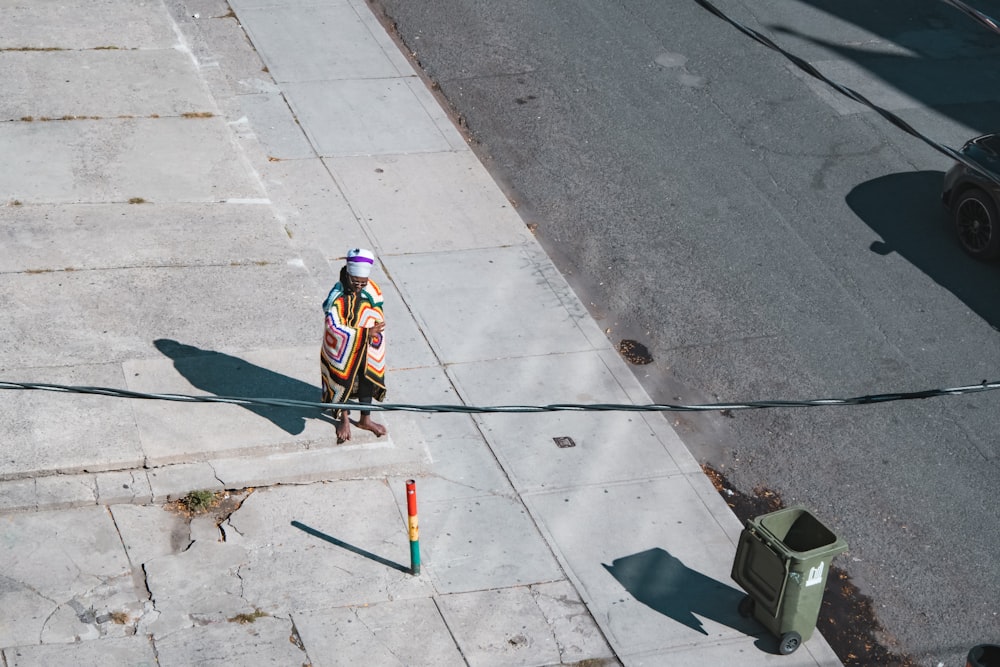 a person standing on a sidewalk near a street