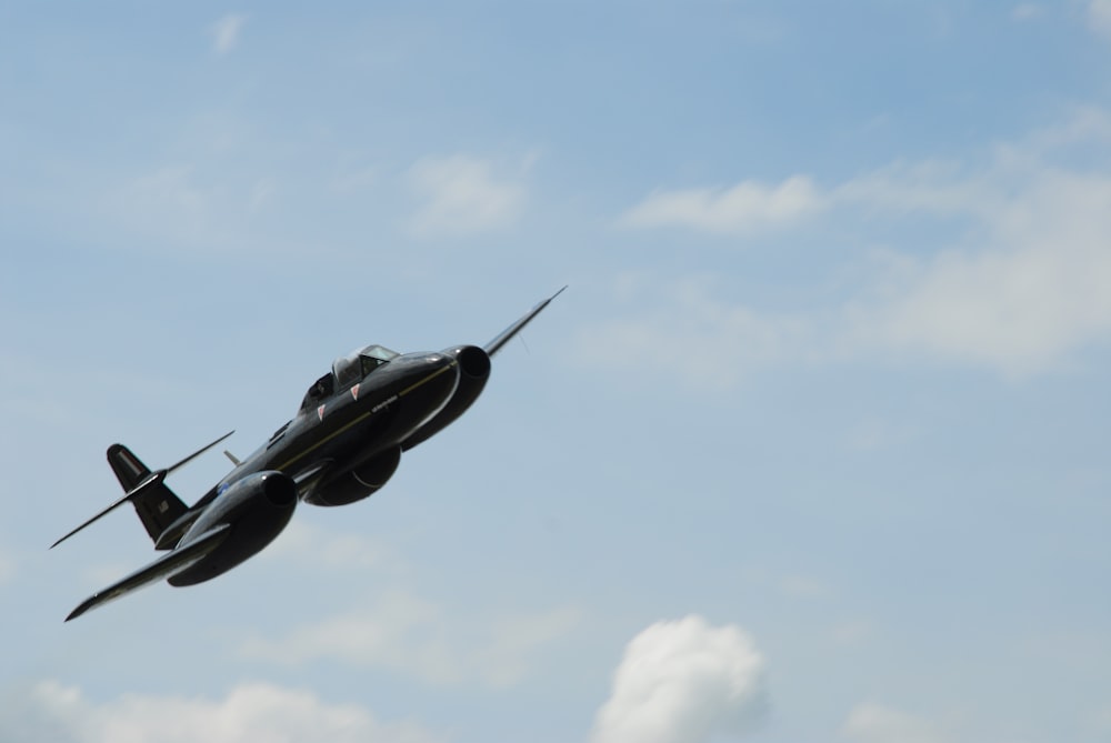 a small airplane flying through a cloudy blue sky