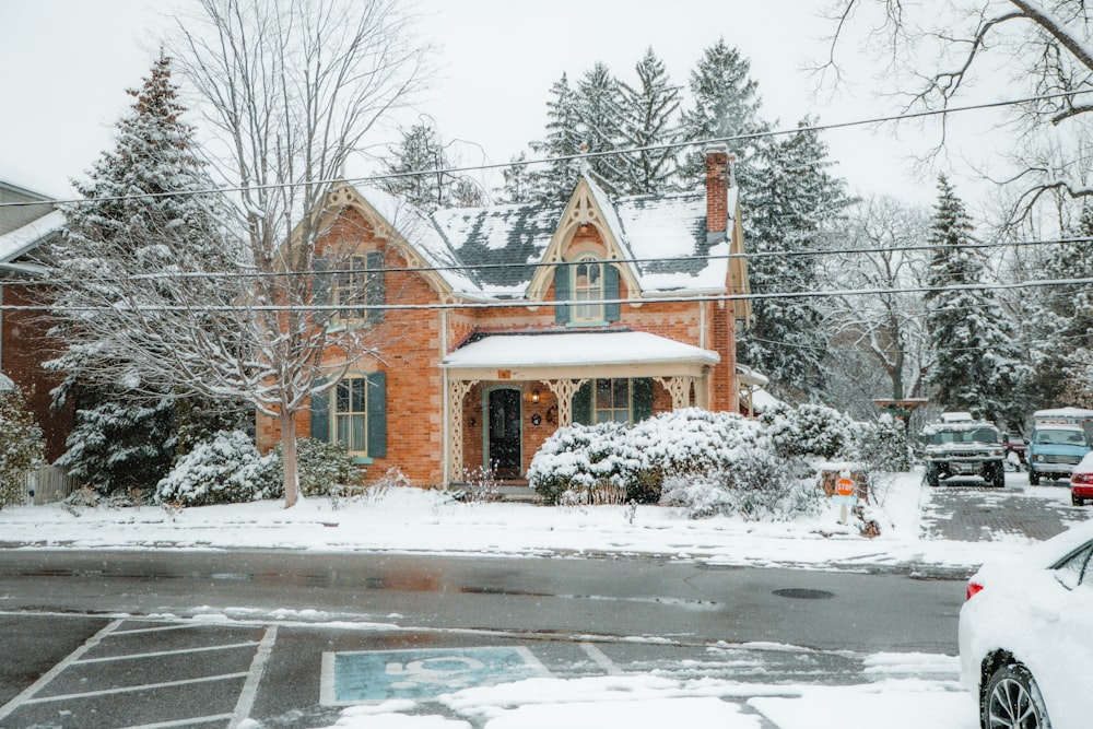 a red brick house covered in snow next to a parking lot