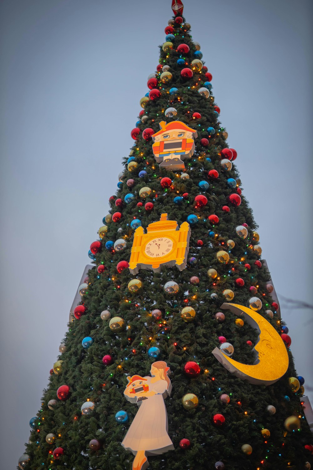 a large christmas tree with decorations and a clock on it