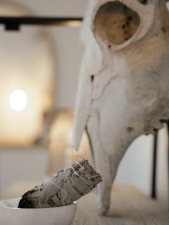 Smoke rising from a ceremonial smudge bowl surrounded by colorful blankets.