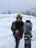 A man smiling while adjusting his snowboard gear in a snowy mountain setting.