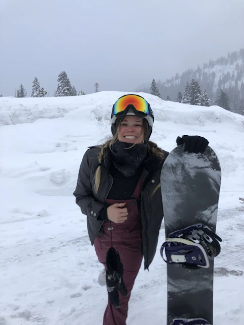 A smiling customer holding their newly leased skis outside the Glidepeak shop