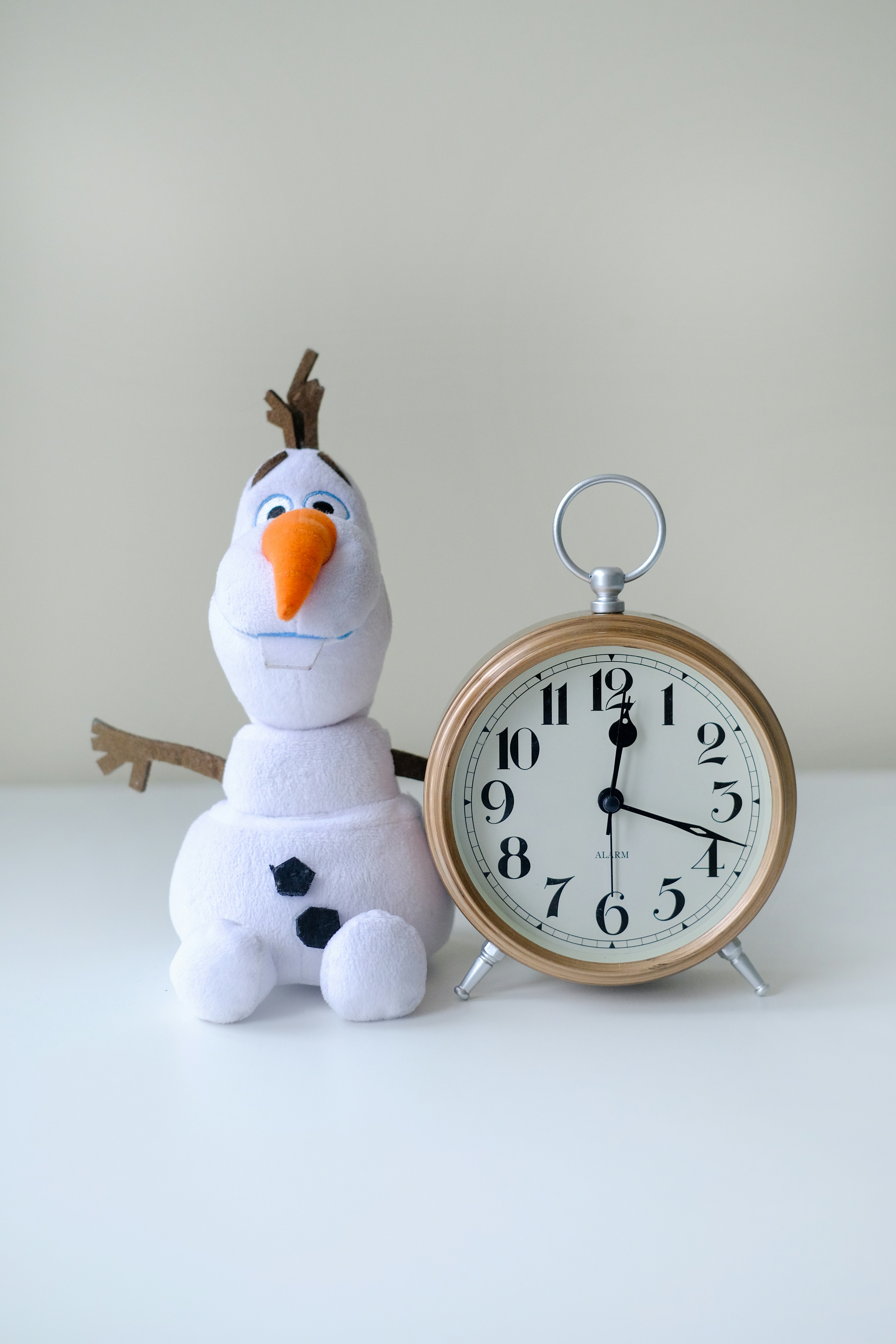 un bonhomme de neige assis à côté d’un réveil