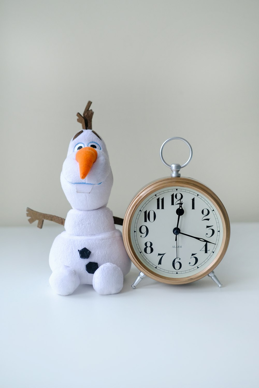 a snowman sitting next to an alarm clock