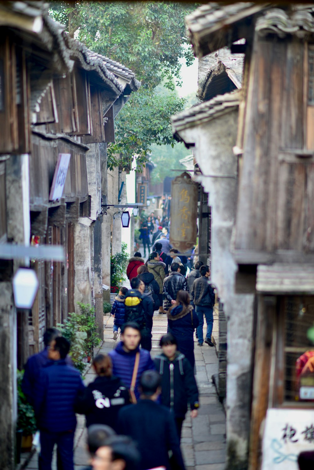 a group of people walking down a street next to wooden buildings