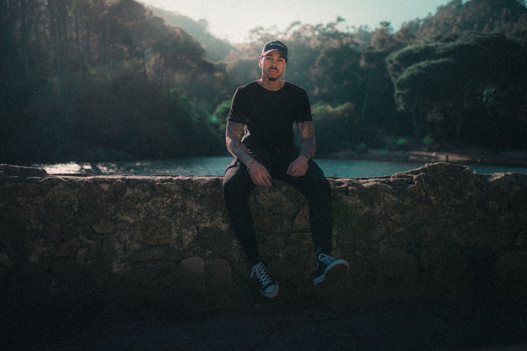 a man sitting on a stone wall next to a river,