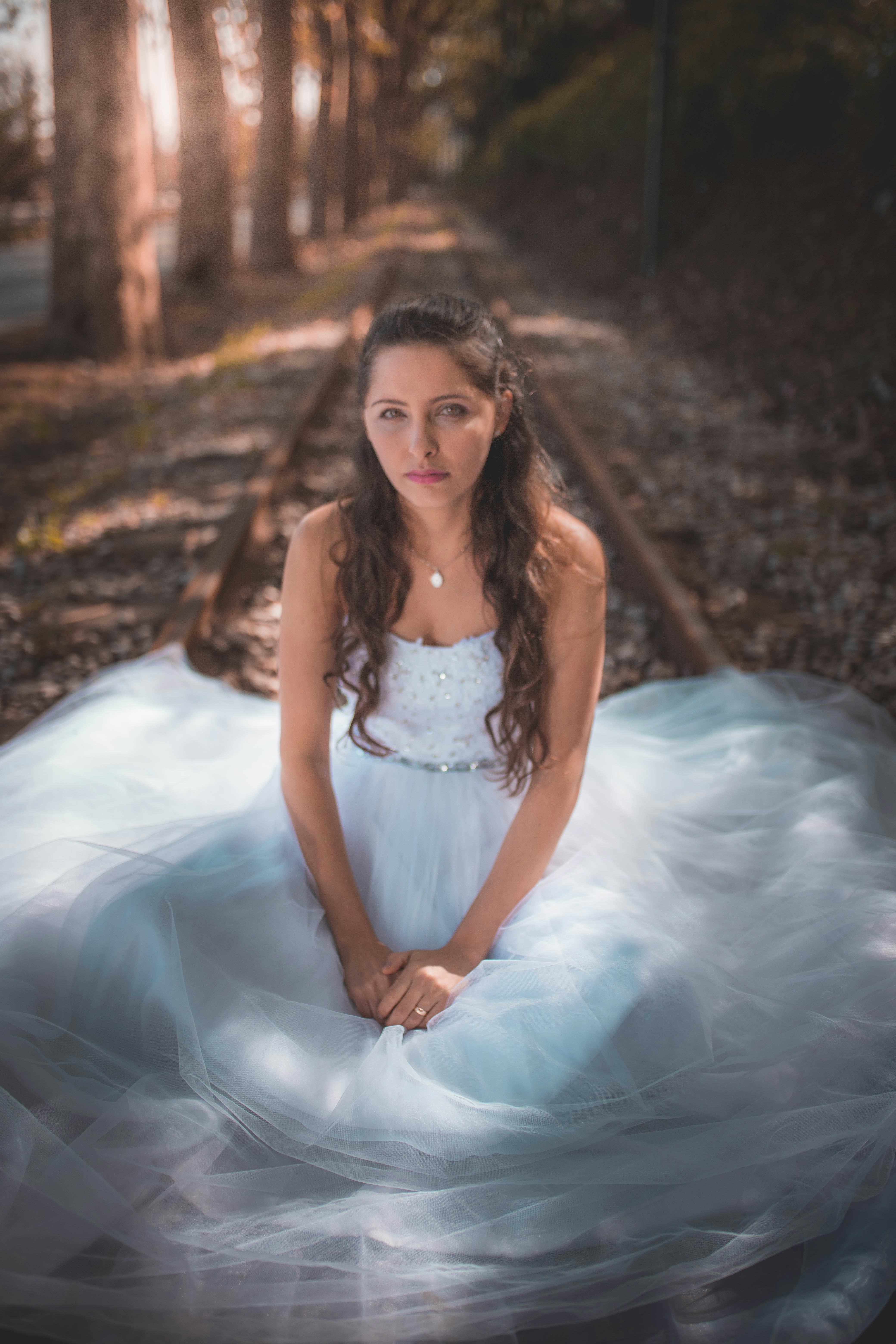 a woman in a white dress sitting on a train track