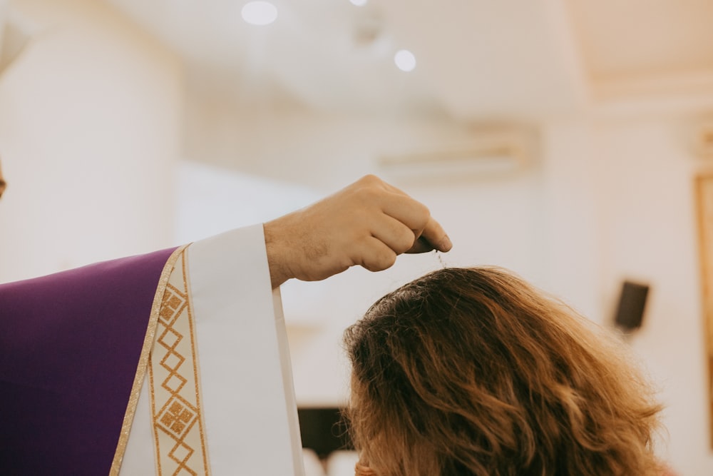 a woman getting her hair done by a priest