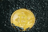 a bit coin sitting on top of a pile of black rocks
