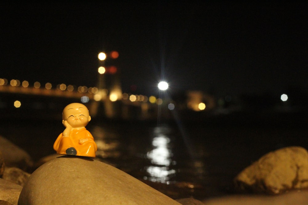 a small toy sitting on top of a rock next to the ocean