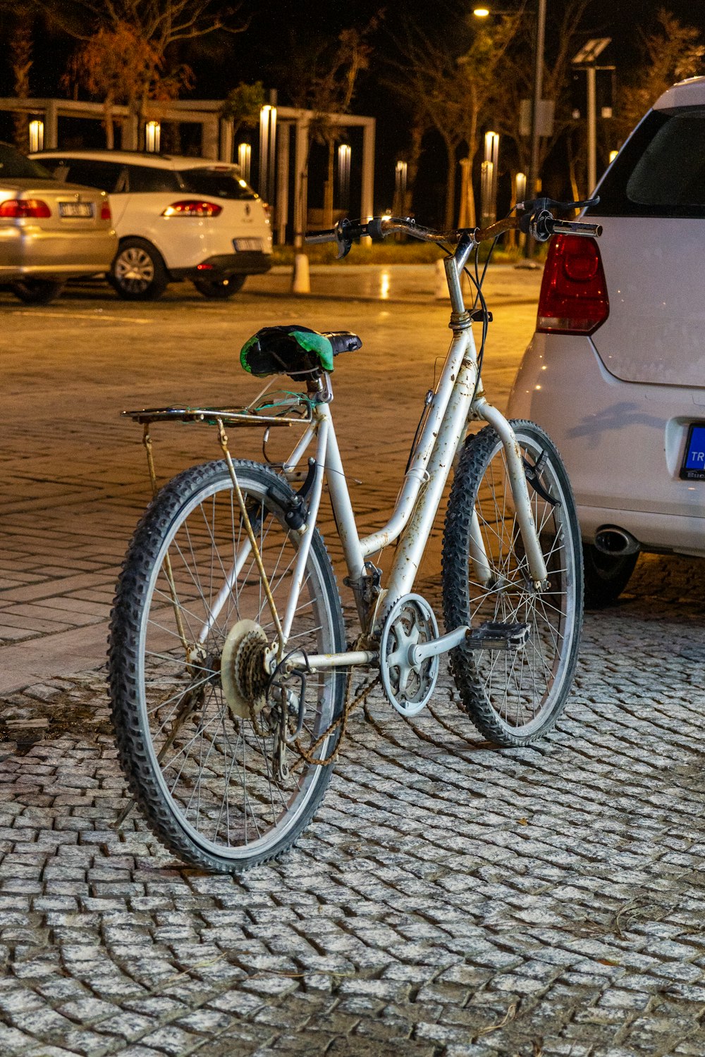 a bike parked on a cobblestone street next to a white car