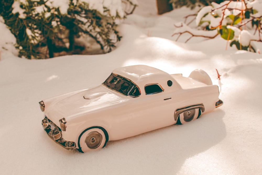 a white toy car sitting in the snow