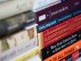 Close-up of beautifully designed book covers stacked on a wooden table at a Faithful Press event.