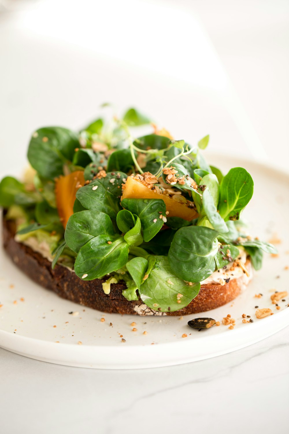 a white plate topped with a piece of bread covered in veggies