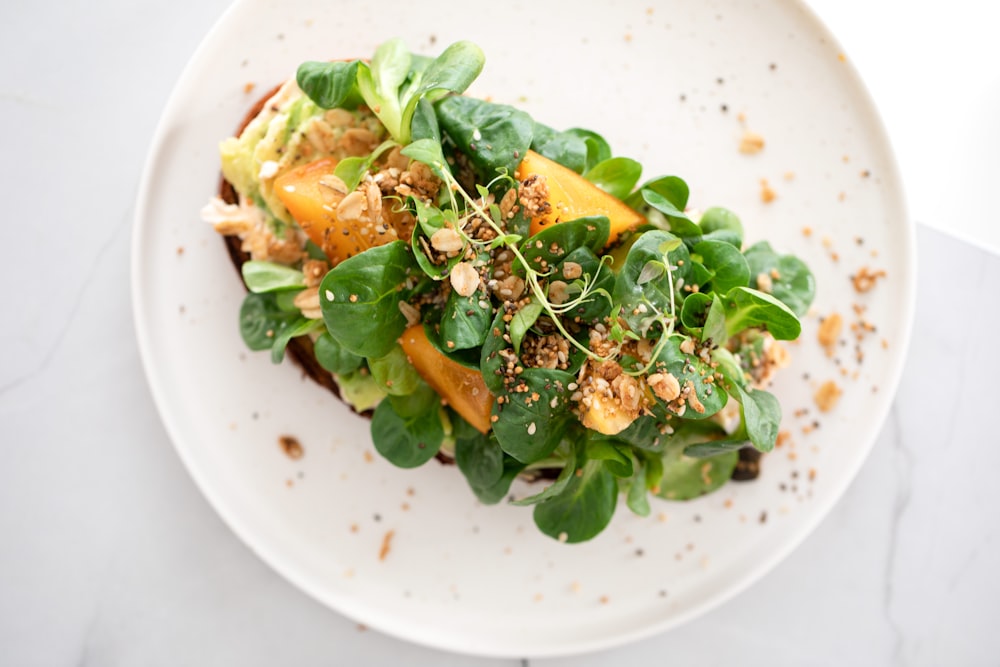 un piatto bianco condito con un'insalata verde