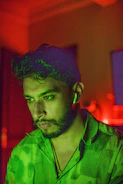 Close-up of a thoughtful man wearing headphones, surrounded by soft teal and lavender abstract shapes.
