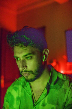 Close-up of a thoughtful man wearing headphones, surrounded by soft teal and lavender abstract shapes.