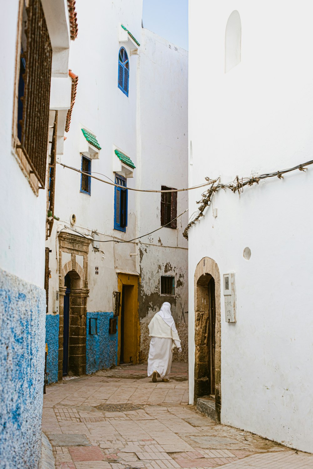 uma pessoa em um manto branco andando por uma rua
