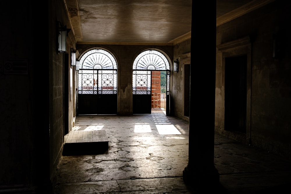 a dark hallway with arched windows and a bench