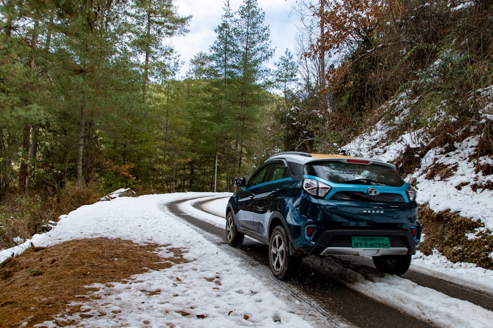 a blue car driving down a snowy road