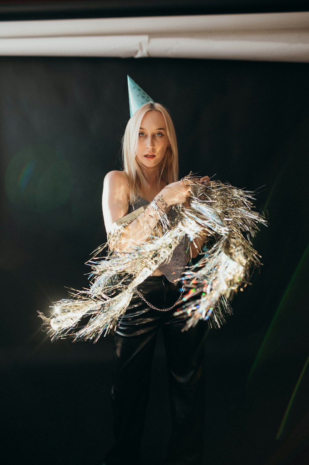 a woman in a party hat holding a bunch of feathers