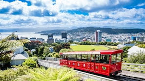 a red trolley on a track with a city in the background