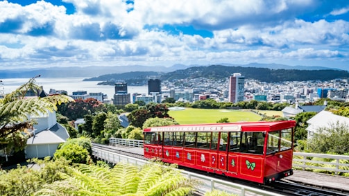 a red trolley on a track with a city in the background