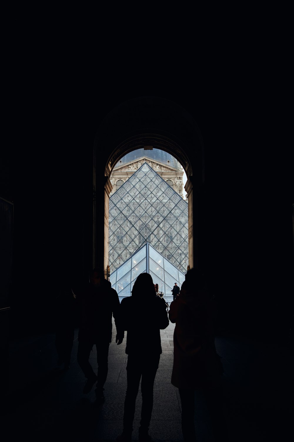 a group of people standing in front of a glass pyramid