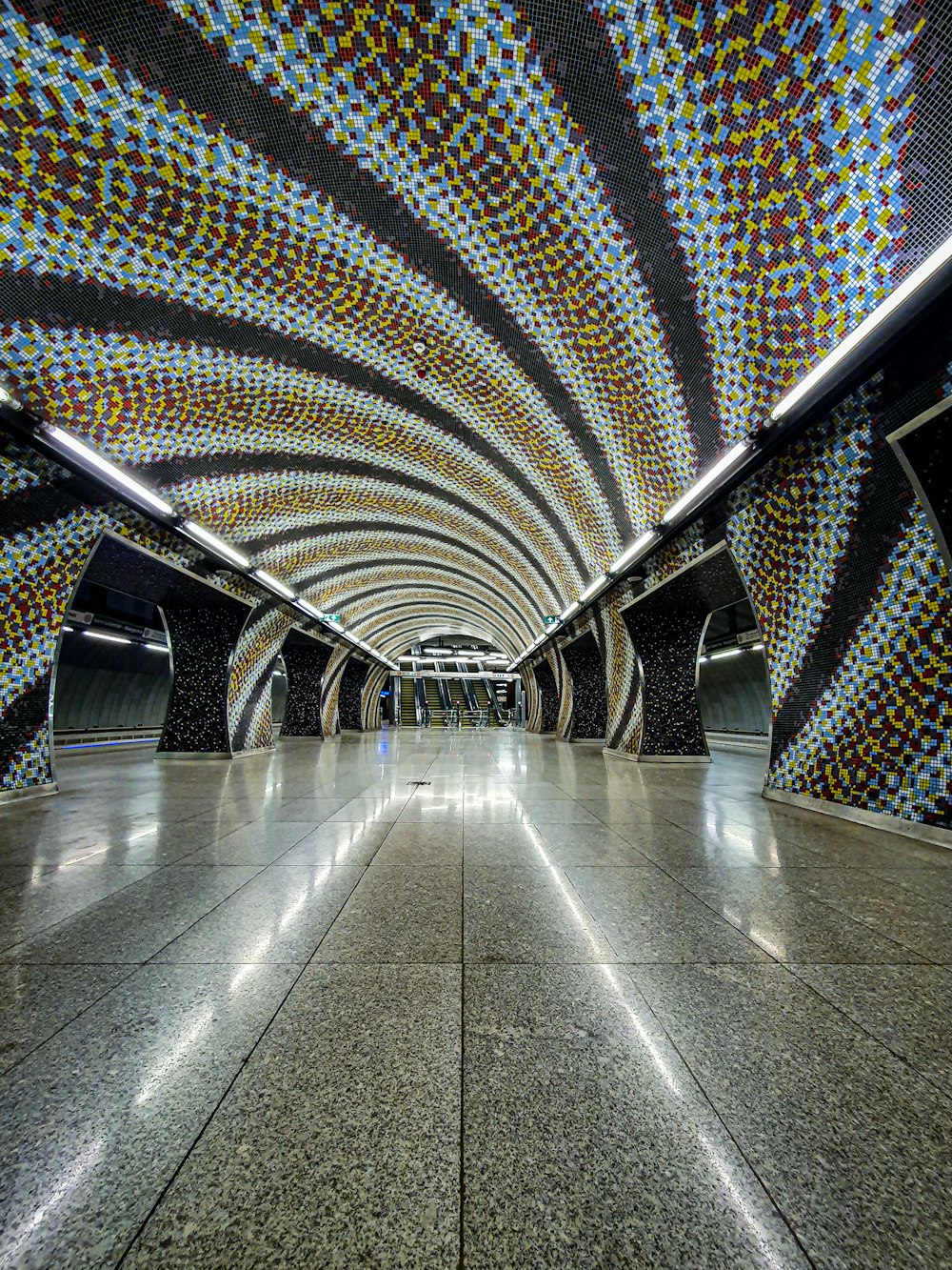 a subway station with a very colorful ceiling