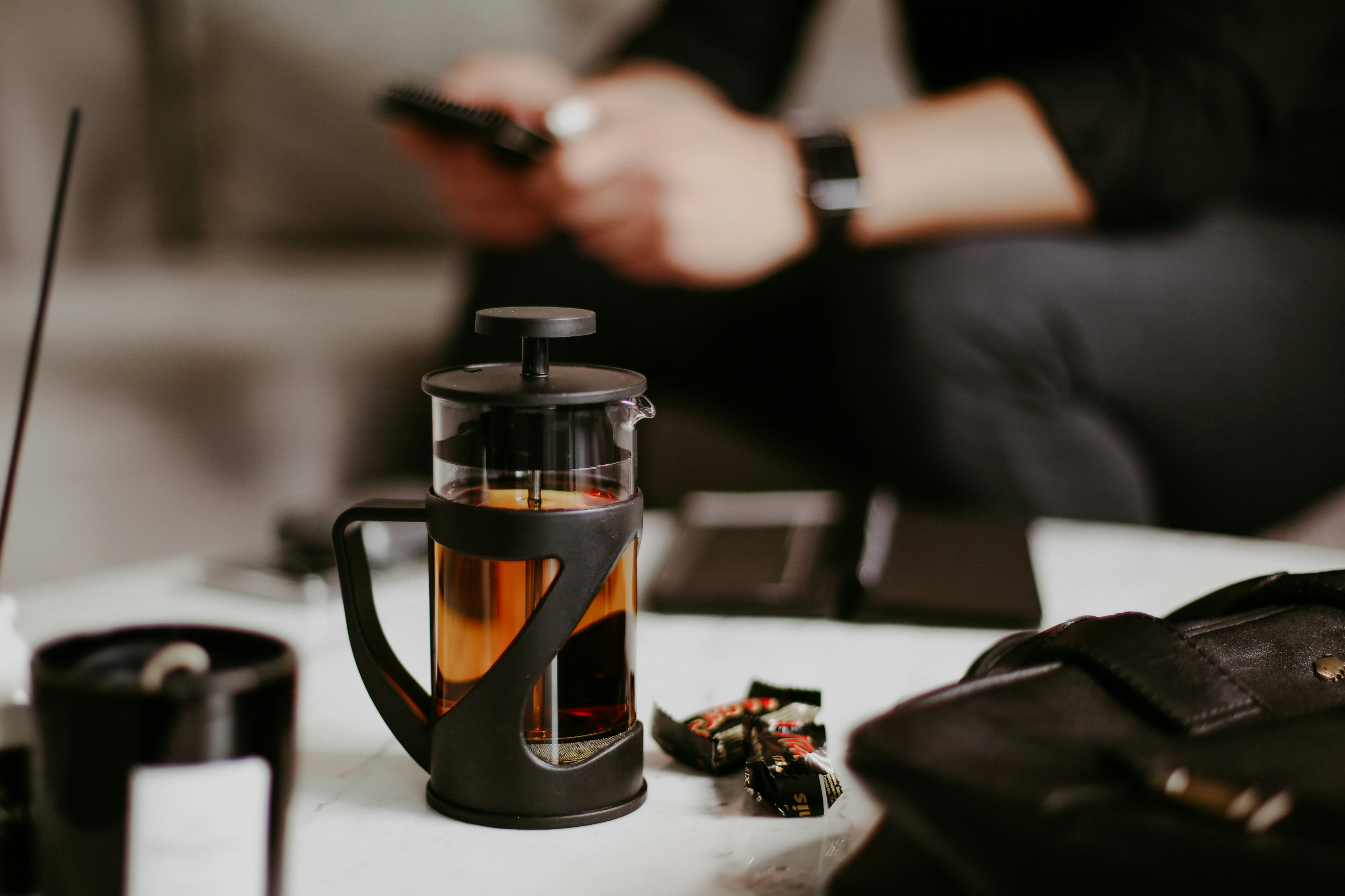 una persona seduta a un tavolo con in mano un telefono cellulare