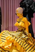 A mannequin dressed in a vibrant yellow classical dance costume with intricate patterns.