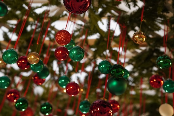 Cheerful Christmas ornaments hanging on a pine tree.