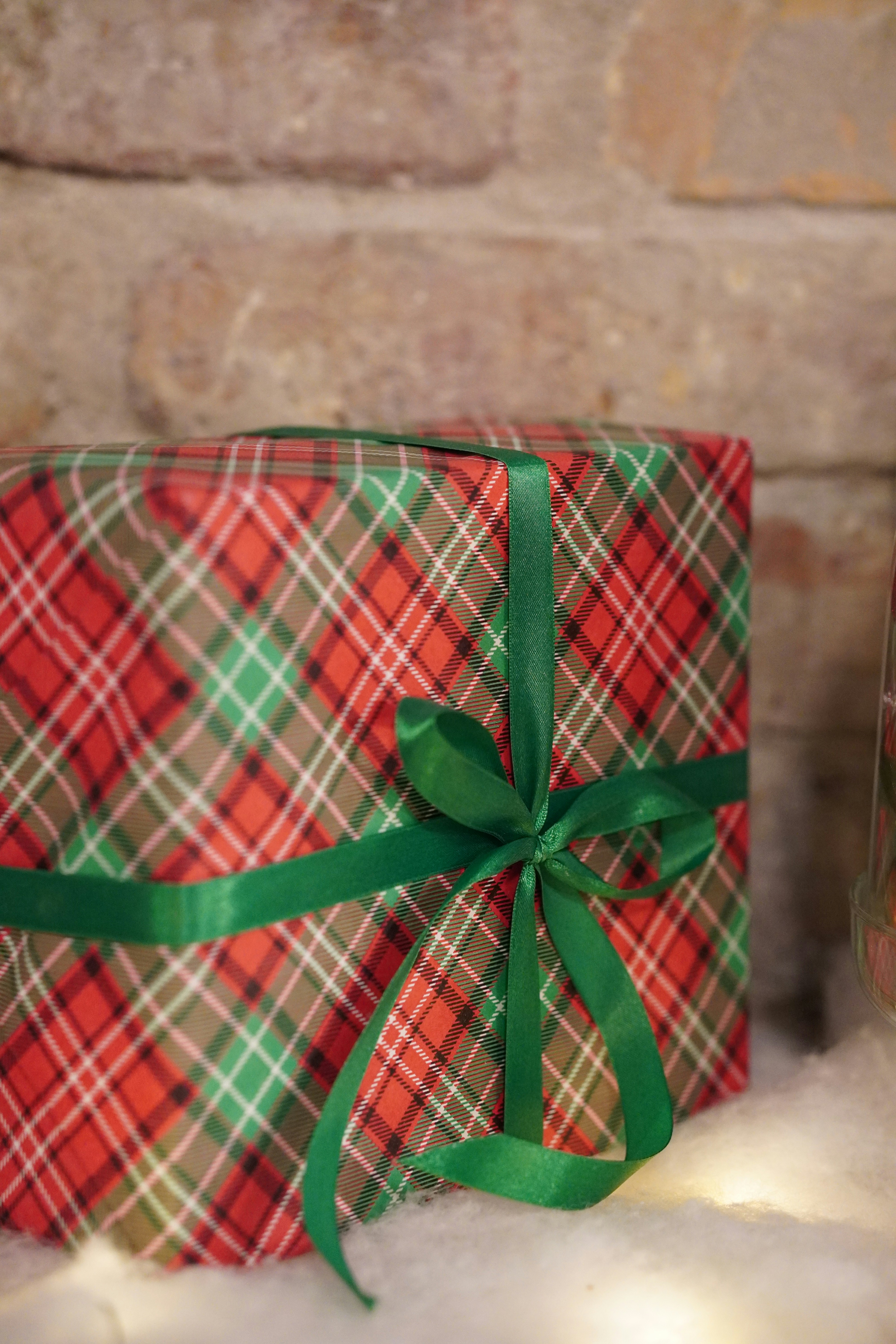 a red and green wrapped present sitting on top of a pile of snow