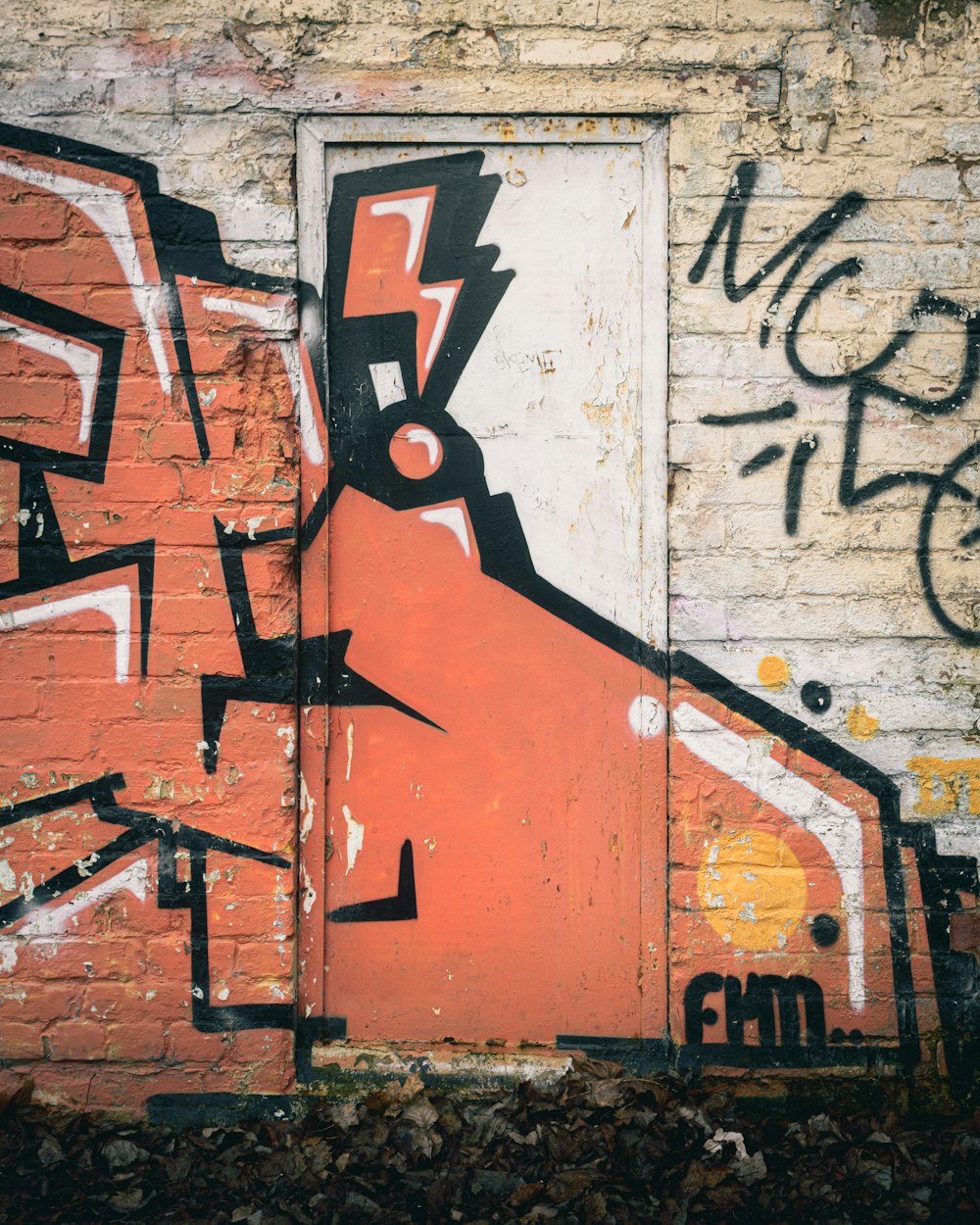 a brick wall with a door and graffiti on it