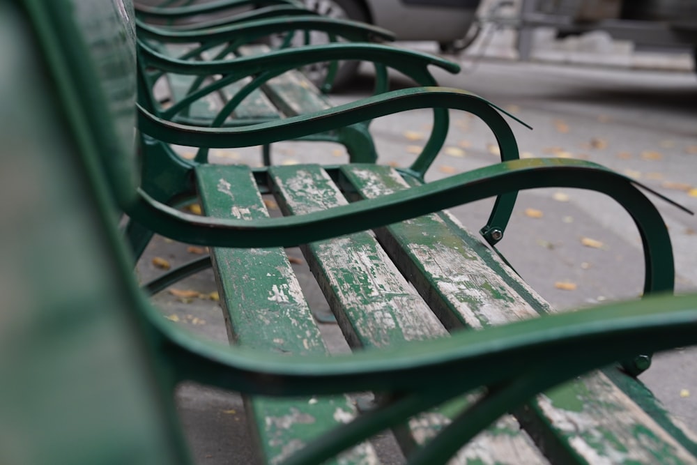 a row of green park benches sitting next to each other