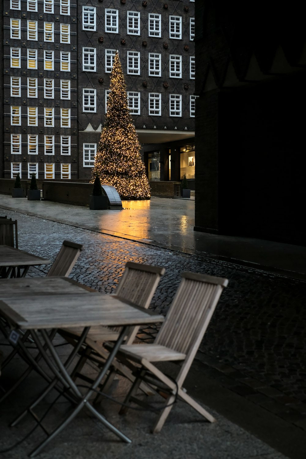 a table and chairs with a lit christmas tree in the background