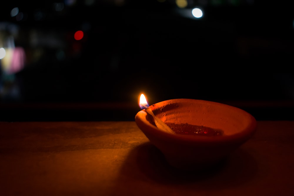 a lit candle sitting in a bowl on a table