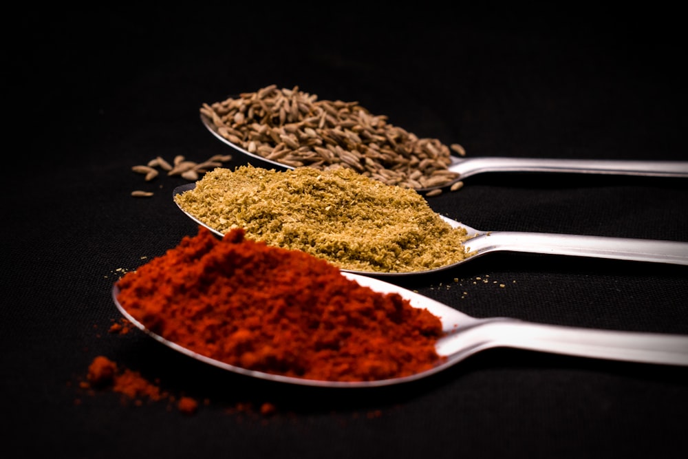 three spoons filled with different types of spices