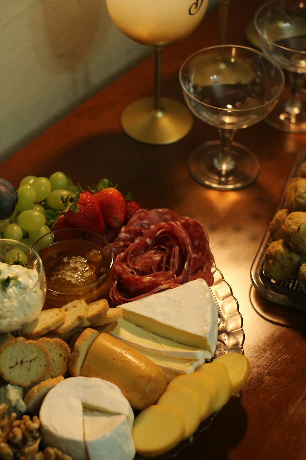 a platter of cheeses, meats, and fruit sits on a table