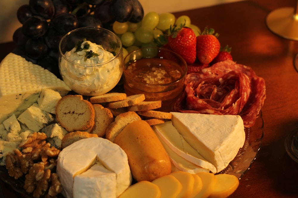 un plato de queso, galletas, frutas y nueces