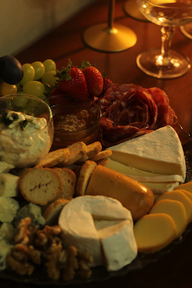 a platter of cheeses, crackers, and fruit on a table