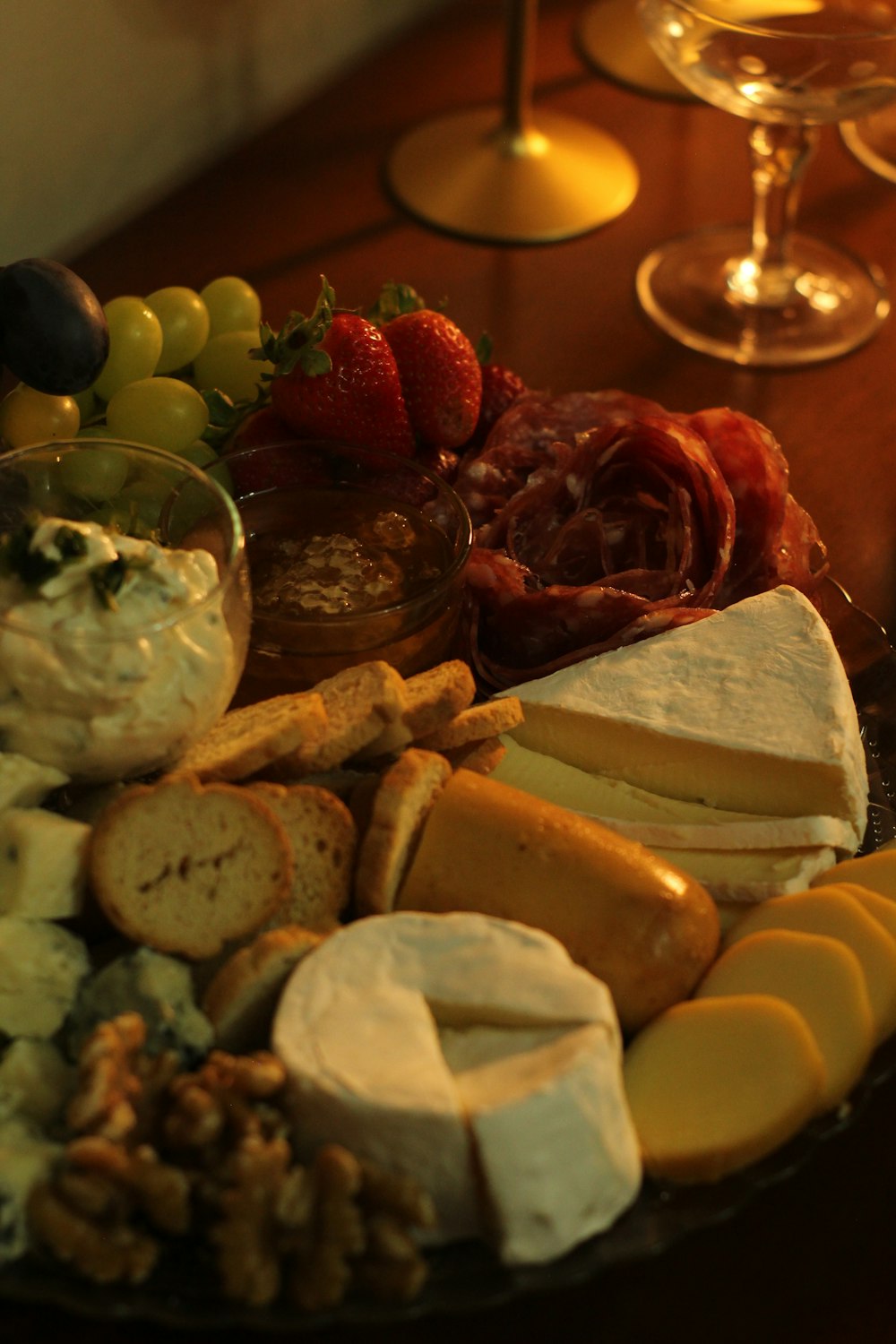 a platter of cheeses, crackers, and fruit on a table