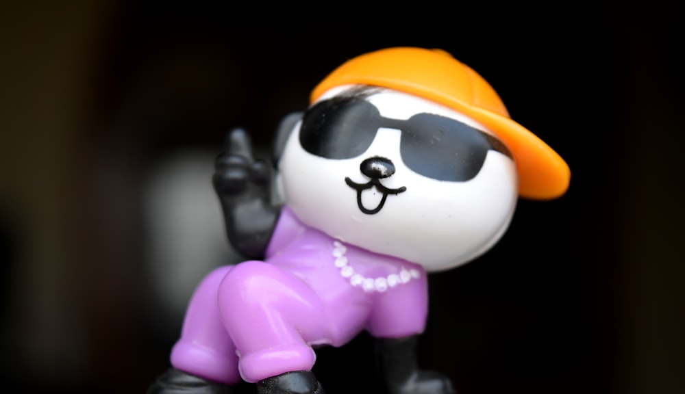 a small figurine of a panda bear wearing a hat and sunglasses