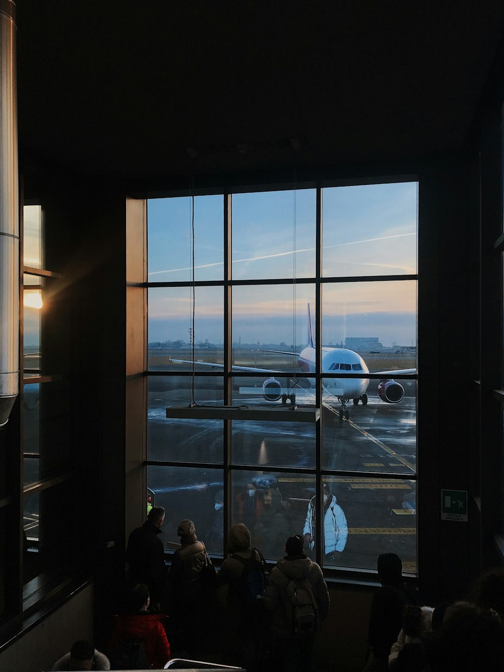 a group of people looking out a window at an airplane