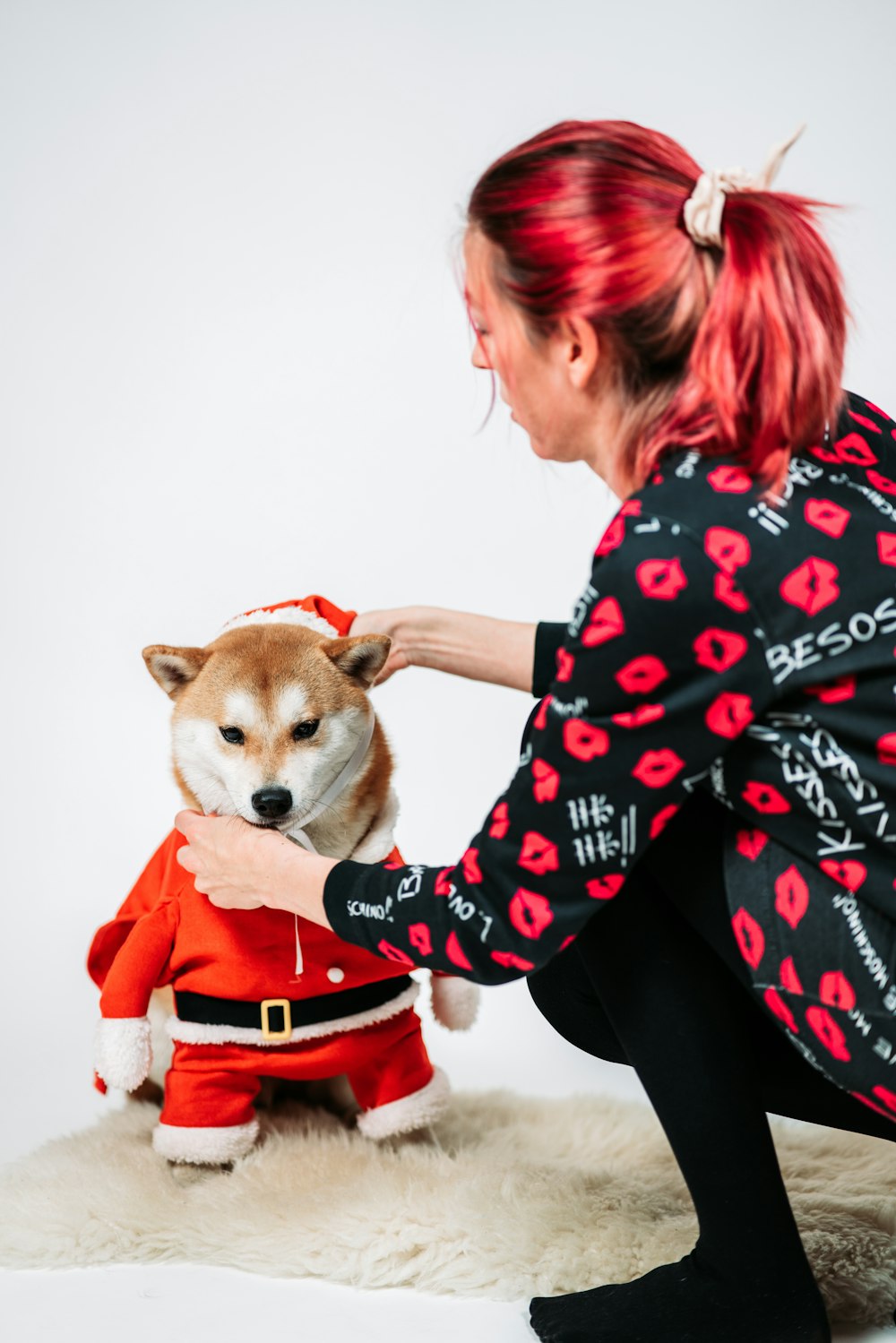 Una mujer acariciando a un perro pequeño vestido con un traje rojo