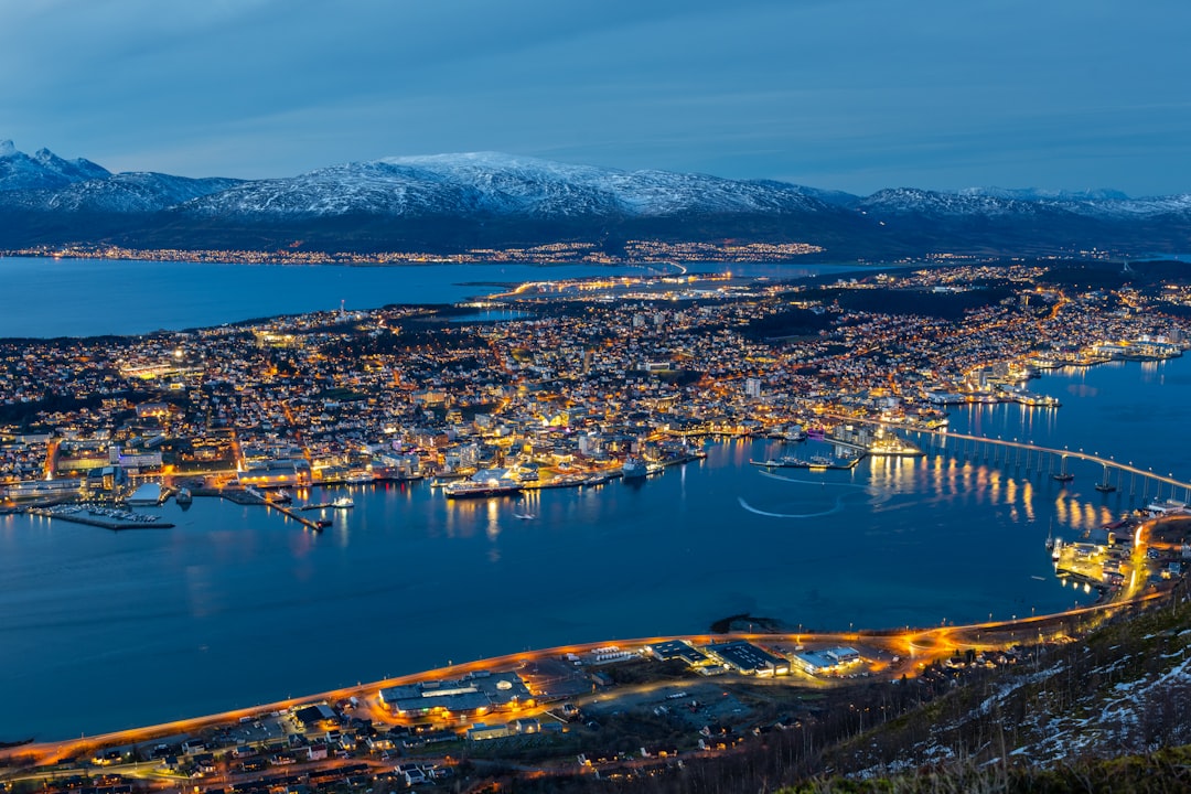 a city lit up at night with mountains in the background, Tromsø city at night from Fløya mountain