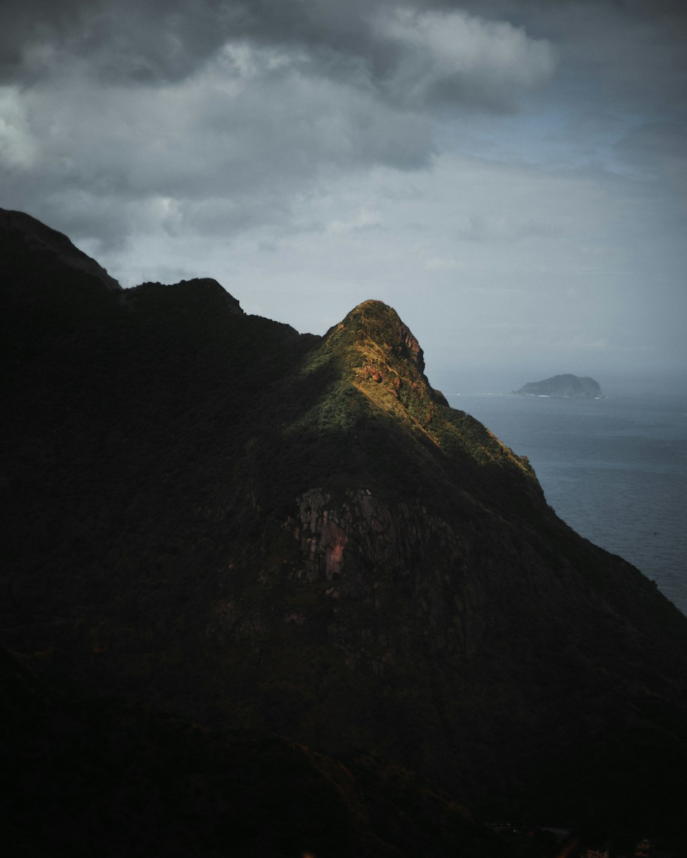 a large mountain with a small island in the distance