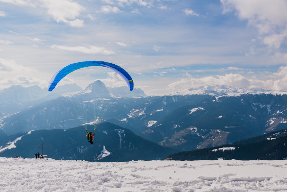 a paraglider flying over a snow covered mountain range